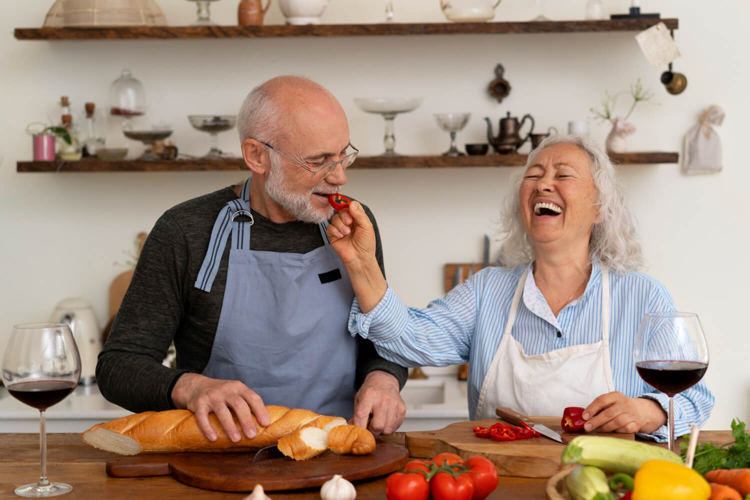 Casal idoso sorrindo e cozinhando alimentos variados após tratamento com prótese dentária na Clínica Saraiva Odontologia em Perdizes.